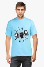 A person wearing the Premium Fitness T-Shirt for Health & Fitness Enthusiasts by Looga, which is light blue and features a graphic of a hand gripping a dumbbell on the front. The shirt is stylishly paired with dark jeans, set against a plain white background.