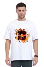 A person wearing an oversized unisex t-shirt from Looga, featuring an orange and black "Born to Play" graphic. The design includes abstract splashes and basketball elements, making a bold statement against the plain white backdrop.