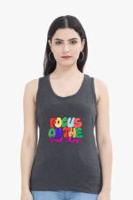 A person with long dark hair, adorned with hoop earrings and wearing a dark tank top featuring the colorful message "Focus on the Good Things," exudes a mysterious allure reminiscent of Looga style. The plain white background accentuates their striking presence, highlighting the Inspirational Tank Top for Women & Girls by Looga.
