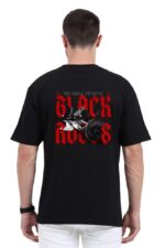 A man sporting a Unisex Oversized T-Shirt from Looga displays the bold style of this piece, featuring a striking image of black roses with large red text that reads BLACK ROSES and smaller text above stating YOU SMELL PATHETIC. The overall design exudes Looga-inspired vibes as he turns to reveal the back of the shirt.