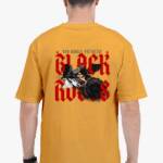 A man showcasing the back of a yellow oversize t shirt with a bold red and black graphic