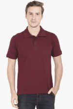 Wearing a burgundy Premium Cotton Polo T-Shirt, a person stands against a light background in dark jeans with one hand in their pocket, exuding calm confidence similar to a laid-back looga.