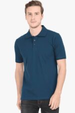 A person poses against a plain white background in a teal Polo T Shirt for men, made from premium cotton with a three-button placket and short sleeves. They wear dark jeans, capturing the minimalist aesthetic of Looga, and maintain a neutral expression while looking at the camera.