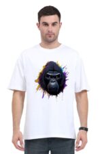 A man wearing an unmistakable Looga style unisex oversized classic T-shirt, featuring a vibrant graphic of a gorilla's face with a colorful splash design, stands against a plain white background. He's complementing his look with dark jeans and a black wristwatch.