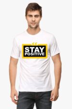 A person wearing the Inspirational T Shirt from Looga, showcasing the "Stay Positive" design with bold black lettering within a yellow-bordered rectangle on a white background, captures the calming essence of the brand.