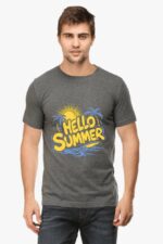 A man in the Classic Summer T-Shirt by Looga, featuring HELLO SUMMER and sun with palm tree graphics, stands facing forward in jeans, capturing the laid-back vibe of a summer evening.