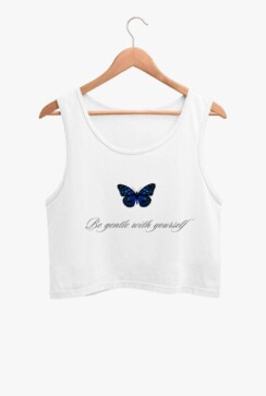 A white crop tank top with a blue butterfly graphic on the front, hanging on a wooden hanger against a plain background.