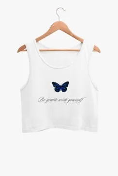 A white crop tank top with a blue butterfly graphic on the front, hanging on a wooden hanger against a plain background.