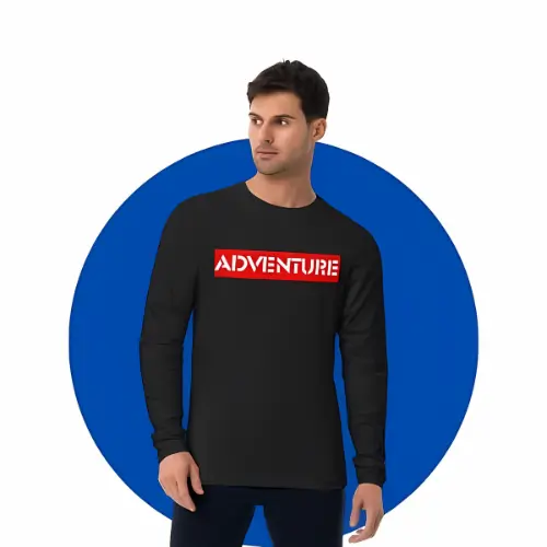 Man in black full sleeve t-shirt with bold ‘ADVENTURE’ print standing against blue backdrop