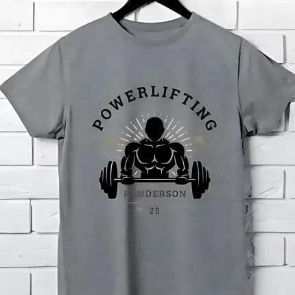 The image depicts a grey t shirt with the bold text “POWERLIFTING” at the top and an illustration of a figure performing a bench press exercise below. The name “HENDERSON” and number “20” are also featured, suggesting a sports theme related to powerlifting gym and fitness.