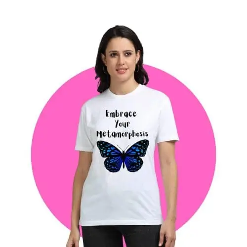 A women wearing a white t-shirt with ‘Embrace Your Metamorphosis’ quote and blue butterfly graphic against pink backdrop