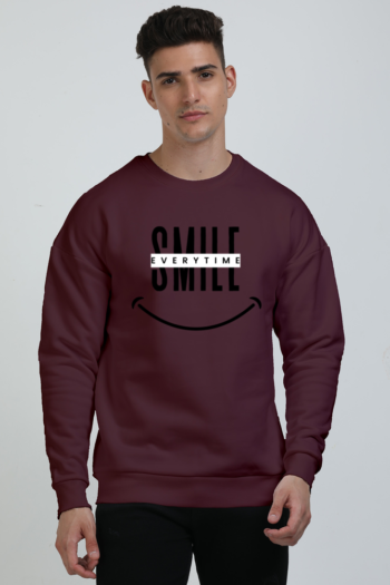 A person wearing a unisex oversized sweatshirt in a deep maroon color. The sweatshirt has a graphic print in the center.