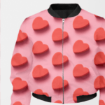 A pink bomber jacket for women with a design of red, three-dimensional hearts scattered across. The jacket has a black collar, cuffs, and hem.
