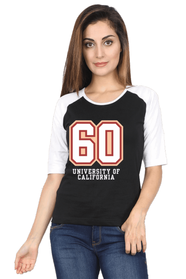 A woman with long hair is wearing a black and white raglan t-shirt featuring the number 60 and the words University of California. She is also wearing blue jeans and standing against a plain background.