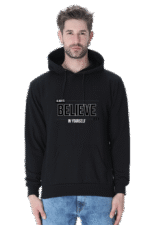 A person wearing the Hooded Sweatshirt in black, featuring the text Always Believe in Yourself and a subtle logo design, stands facing forward. The sweatshirt includes a front pocket and pairs perfectly with light blue jeans.
