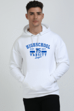 Wearing an oversized white hoodie with HIGH SCHOOL 75 VARSITY League in blue, a person stands confidently against a plain background. This unisex sweatshirt is perfect for Looga enthusiasts, offering style and convenience with its handy front pocket.