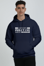 A person in an oversized dark blue hooded sweatshirt, printed with Always Keep a Positive Mindset in white on the front, stands against a plain backdrop. The unisex design offers comfort and classic looga style with its drawstring hood.