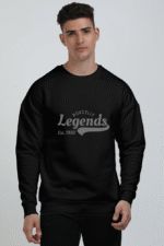 A person dons a cozy oversized Legends: Est. 1950 black sweatshirt against a plain backdrop.