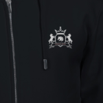 A person wears a thick, embroidered black hoodie with a silver emblem on the chest featuring two horses, a shield, and a crown beneath SINCE 2013. The hoodie includes a zipper and drawstrings.